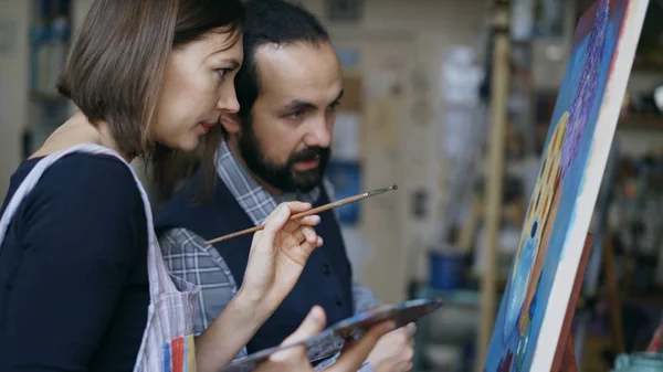 Geschoolde kunstenaar leraar tonen en bespreken van de basisprincipes van het schilderij te student aan kunst-klasse — Stockfoto