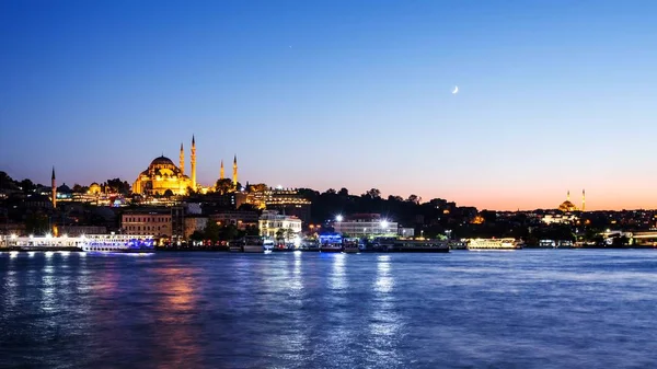 Paisaje urbano de Estambul con mezquita Suleymaniye con barcos turísticos flotando en el Bósforo por la noche — Foto de Stock