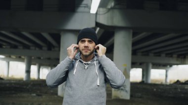 Sportif yakışıklı runner üzerine koyarak kulaklık ve kışın açık havada şehir konumda çalışan başlatır