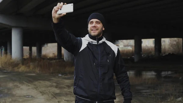 Homem esportivo feliz tomando retrato selfie com smartphone após o treinamento em localização urbana ao ar livre no inverno — Fotografia de Stock