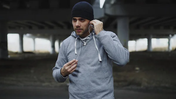 Beau sportif homme coureur portant des écouteurs et commence à courir à l'extérieur urbain emplacement de la ville en hiver — Photo