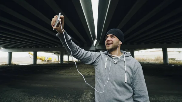 Muž sportovec s video konverzaci o smartphone s jeho trenér po cvičení v městských umístění venku v zimě — Stock fotografie
