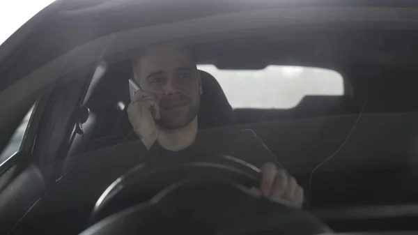 Atractivo hombre de negocios feliz charlando teléfono inteligente mientras está sentado dentro de su coche al aire libre —  Fotos de Stock