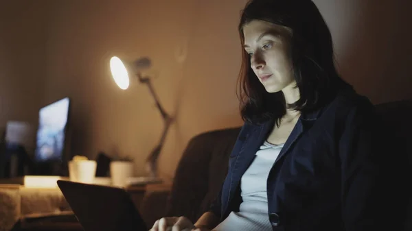 영 집중 노트북 컴퓨터를 사용 하 여 메시지를 입력 하는 밤에 일 하는 여자 스톡 이미지