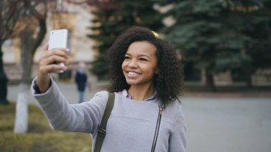 Neşeli karışık yarış öğrenci kız Üniversitesi yakınındaki smartphone ile görüntülü görüşme, söz