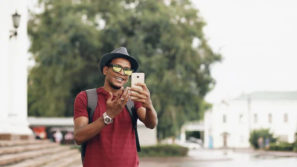 आनंदी आफ्रिकन अमेरिकन पर्यटक मनुष्य युरोप प्रवास करताना त्याच्या स्मार्टफोन कॅमेरा वापरून ऑनलाइन व्हिडिओ गप्पा येत — स्टॉक फोटो, इमेज