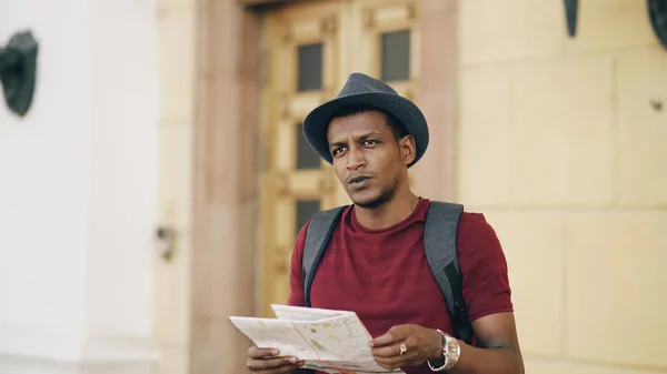 Un touriste afro-américain se penche sur une carte de la ville en papier explorant les sites touristiques pendant un voyage en Europe — Photo