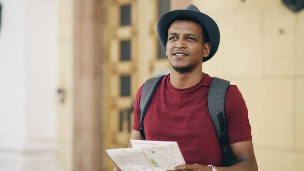 African american tourist man looking into paper city map exploring sightseeings during travelling in Europe