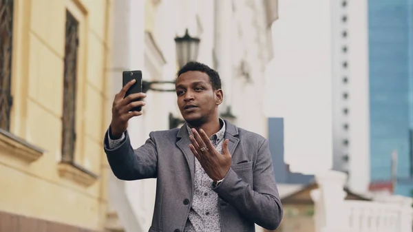Homme d'affaires de race mixte en colère ayant chat vidéo en ligne dans une conférence d'affaires en utilisant un smartphone — Photo