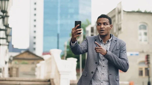Rozzlobený Smíšené rasy podnikatel s online video chatu v obchodní konference pomocí smartphonu — Stock fotografie