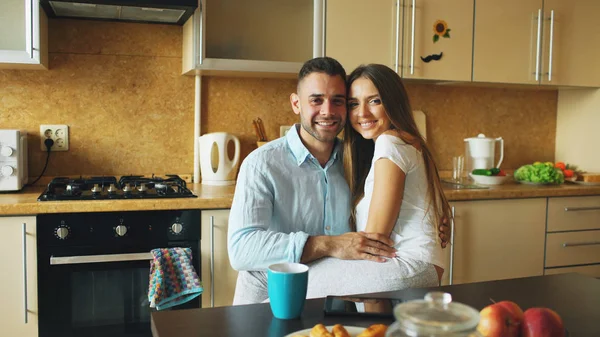 Retrato de feliz pareja sonriente sentada en la cocina temprano en la mañana en casa — Foto de Stock
