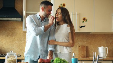 Mutlu genç çift mutfakta. Yakışıklı adam karşılamak ve onun kız arkadaşı erken sabah yem