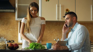 Sabah mutfakta çekici çift. Güzel kız yemek kahvaltı sırasında çalışma ve telefonu konuşurken sevgilisi