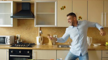 Yakışıklı adam mutfakta kahvaltı evde pişirme sırasında kepçe ve kaşıkla eskrim eğleniyor
