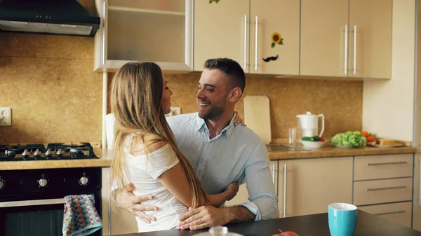 Attraktives junges Paar umarmt frühmorgens in der Küche, während der Mann frühstückt — Stockfoto