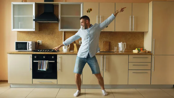 Csinos fiatal vicces ember táncolt konyha otthon reggel, és érezd jól magad a nyaralás — Stock Fotó
