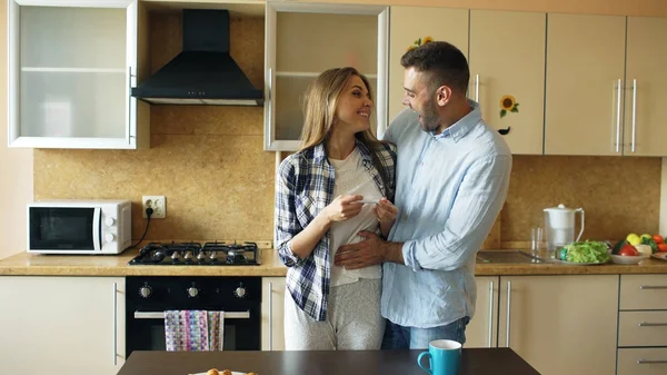 Приваблива дівчина показує результат тесту на вагітність своєму хлопцеві і здивує його на кухні — стокове фото