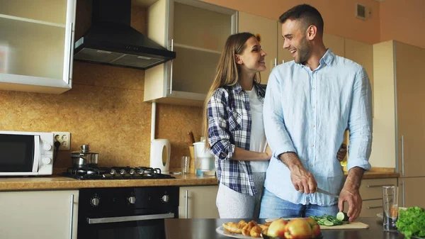 Glückliches junges Paar, das sich umarmt und in der Küche plaudert, während es zu Hause frühstückt — Stockfoto