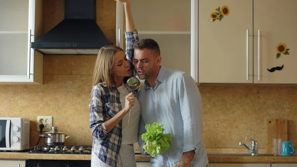 Atractiva pareja alegre joven divertirse bailando y cantando mientras cocina en la cocina en casa — Foto de Stock