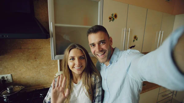 Молодая счастливая пара, имеющая онлайн видео чат на кухне дома — стоковое фото