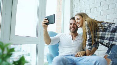 Modern loft daire balkonda oturan tablet bilgisayar kullanarak online görüntülü sohbet sahip genç çekici çift