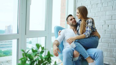 Güzel genç çift sandalyede oturan ve manzarayı yeni loft daire balkon dinlenmek