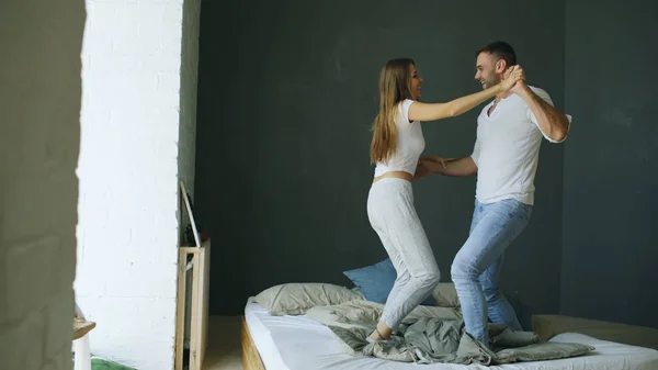 Young beautiful and loving couple dancing on bed in morning — Stock Photo, Image