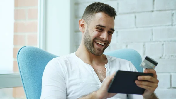 Jovem sorrindo homem fazendo compras on-line usando o computador tablet digital sentado na varanda em casa — Fotografia de Stock