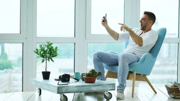 Joven hombre feliz tienen chat de vídeo en línea utilizando la tableta digital de la computadora sentado en el balcón en el apartamento loft moderno — Foto de Stock