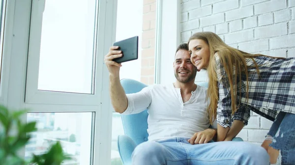 Modern loft daire balkonda oturan tablet bilgisayar kullanarak online görüntülü sohbet sahip genç çekici çift