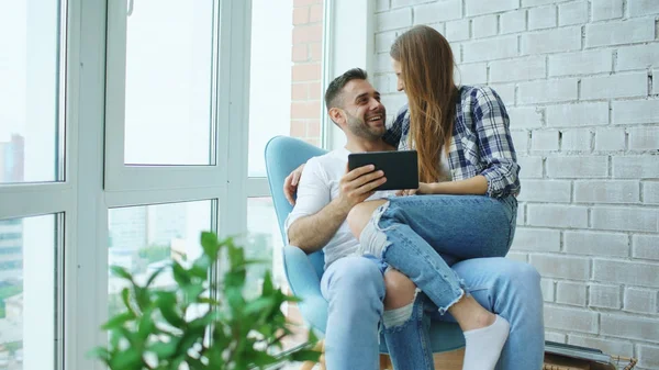 Jovem casal alegre falando e usando computador tablet na varanda no apartamento loft moderno — Fotografia de Stock