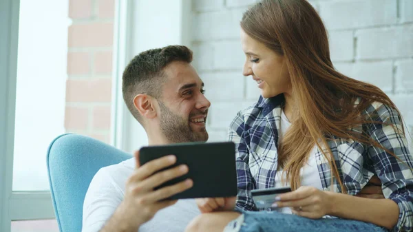 Digitális tábla-PC segítségével az online vásárlás, a vidám fiatal pár ül modern tetőtéri lakás erkéllyel — Stock Fotó