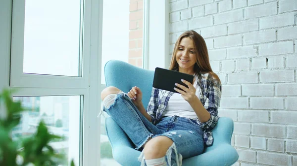 Fiatal, boldog nő már ül a modern tetőtéri lakás erkéllyel felszerelt digitális tábla-PC használata online videó chat — Stock Fotó