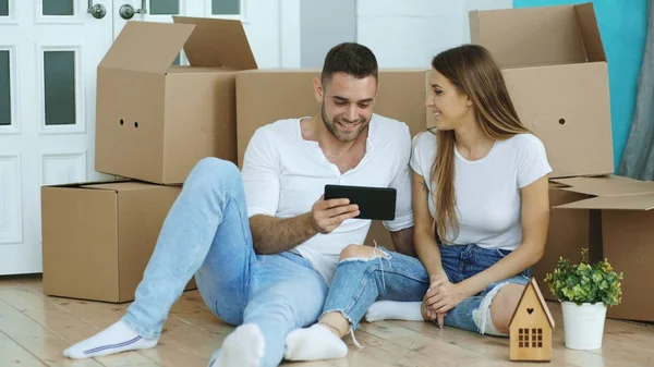 Giovane coppia seduta sul pavimento utilizzando tablet dopo il trasferimento nella loro nuova casa — Foto Stock