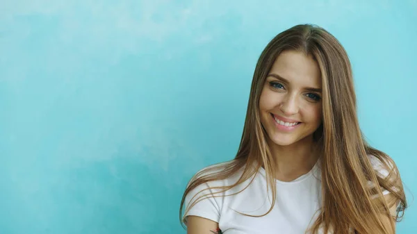 Primo piano ritratto di giovane donna sorridente e ridente che guarda in macchina fotografica su sfondo blu — Foto Stock