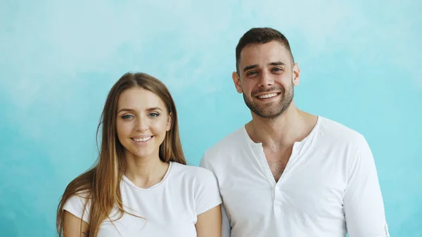 Portret van jonge gelukkige paar glimlachen en lachen in de camera op blauwe achtergrond — Stockfoto