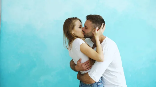 Молодая счастливая пара целуется на голубом фоне — стоковое фото