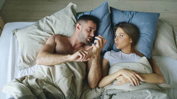 Vue du dessus de jeune couple couché dans le lit bouleversé et se disputer — Photo