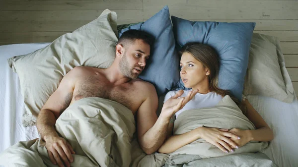 Vue du dessus de jeune couple couché dans le lit bouleversé et se disputer — Photo