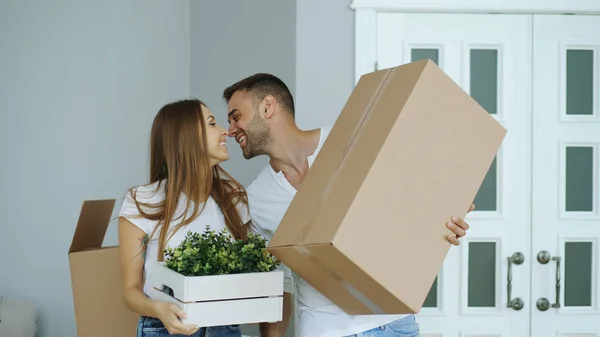 Jovem casal feliz andando em nova casa depois de se mover dia e beijar uns aos outros Fotos De Bancos De Imagens
