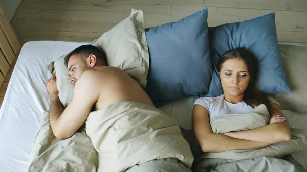 ベッドで横になっている眠れぬカップルが口論のため腹の不調の平面図します。 ストック写真