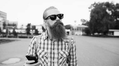 Sakallı turist adam sokakta yürürken ve açık havada daha harita için smartphone kullanarak sırt çantası ile