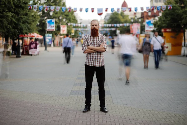 Mladý vousatý muž, který stojí stále na chodníku v davu provozu s lidmi, pohybující se kolem — Stock fotografie