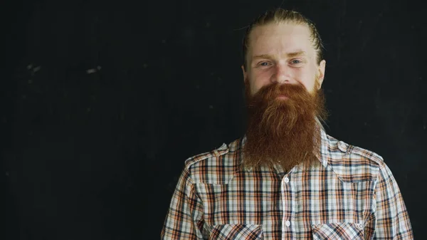 Retrato de close-up do homem hipster olhando para a câmera e sorrindo no fundo preto — Fotografia de Stock