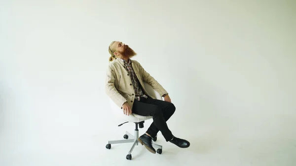 Boring bearded man turning on swivel office chair on white background — Stock Photo, Image