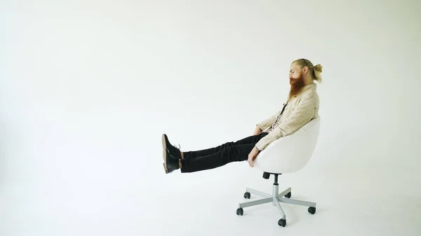 Boring bearded man turning on swivel office chair on white background — Stock Photo, Image