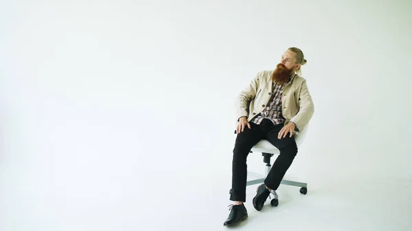 Döner ofis koltuğu beyaz arka plan üzerinde oturan ciddi sakallı adam — Stok fotoğraf