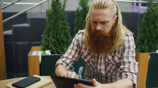 Jeune homme avec tablette d'ordinateur assis dans un café à l'extérieur ayant se détendre et se reposer du travail — Photo