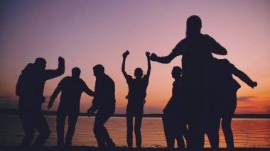 Grup genç insanlar dans silüeti on sunset beach adlı bir parti var