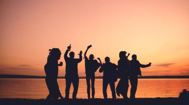 Grup genç insanlar dans silüeti on sunset beach adlı bir parti var